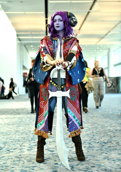 A cosplayer with purple hair and skin poses with a giant sword during New York Comic Con 2023 - Day 1 at Javits Center on October 12, 2023 in New York City.