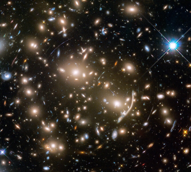 Abell 370 is a galaxy cluster about 4 billion light years from Earth. Its gravity causes light from galaxies behind it to bend, called gravitational lensing. Credit: NASA, ESA, and J. Lotz and the HFF Team (STScI)
