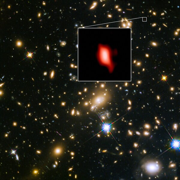 The galaxy cluster MACSJ1149.5+223 lies in the foreground and magnifies the image of the much more distant JD1, a galaxy 13.3 billion light years away. Inset is the observation of oxygen from the galaxy. 