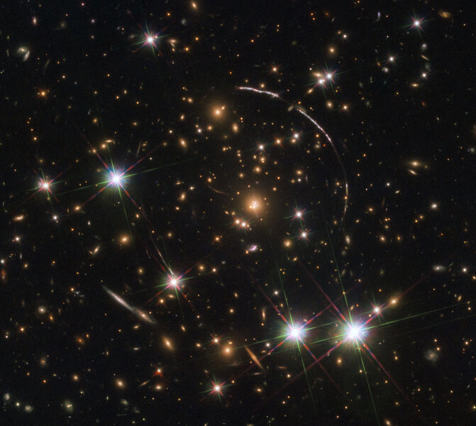 A cluster of galaxies 4.6 billion light years away acts like a lens, distorting, magnifying, and multiply replicating an image of a more distant galaxy 11 bilion light years away into a series of arcs. Credit: ESA/Hubble, NASA, Rivera-Thorsen et al.