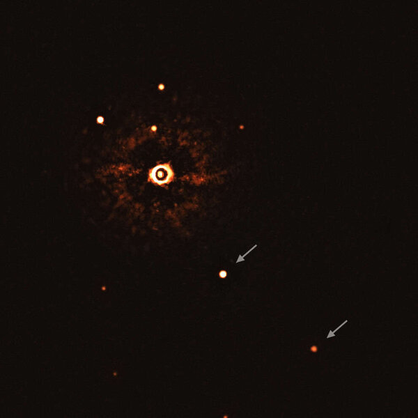 An actual image of two planets (arrowed) orbiting a very Sun-like star, TYC 8998-760-1 (upper left), the glare of which is reduced by blocking its light. The system is young, just 17 million years old, and about 310 light years away. Credit: ESO/Bohn et a