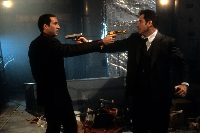 Nicolas Cage and John Travolta aiming guns at each other in a scene from the film 'Face/Off' (1997)