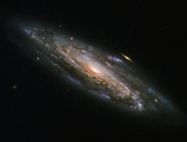 NGC 5559 and a little friend, imaged by Hubble Space Telescope. Credit: ESA/Hubble & NASA