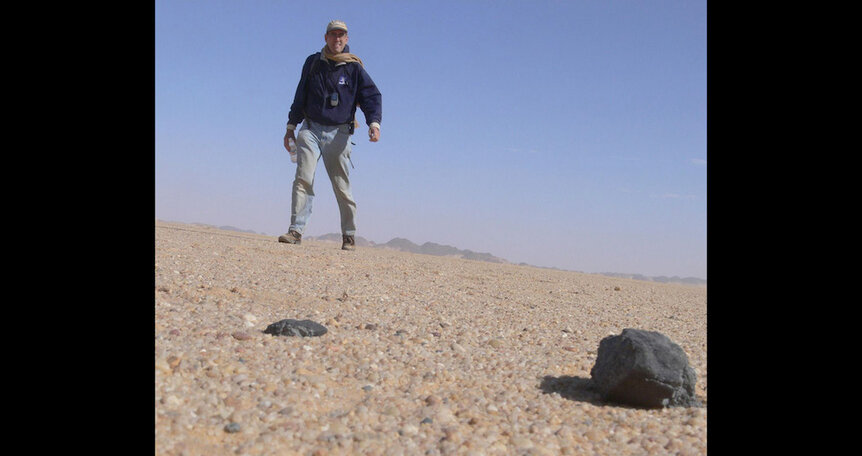 Astronomer Peter Jenniskens approaches a pair of meteorites