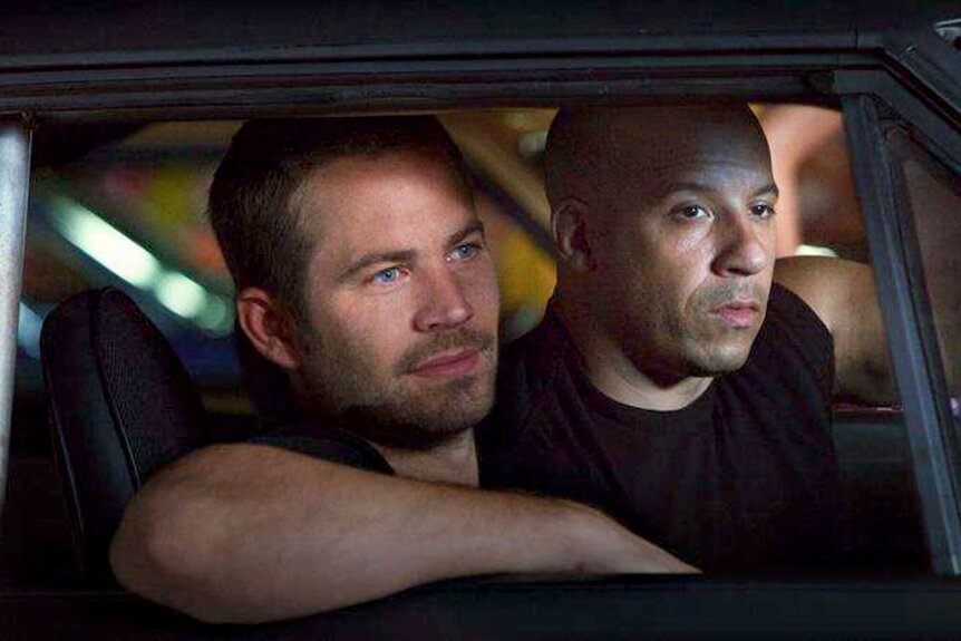 Paul Walker and Vin Diesel sitting in a car in Fast Five