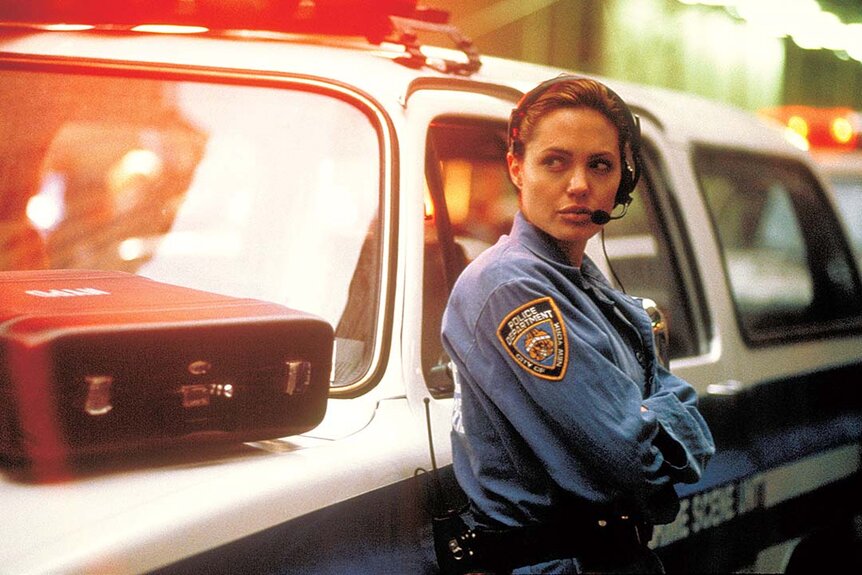 Angelina Jolie as a policeman leaning on a police car in The Bone Collector (1999)