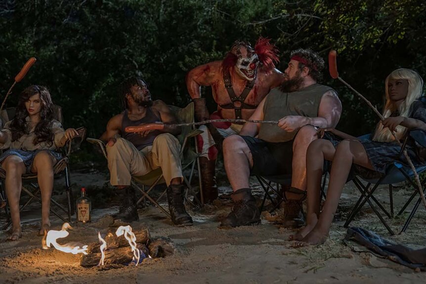 (l-r) Tahj Vaughans as Mike, Joe Seanoa as Sweet Tooth, Mike Mitchell as Stu sit around a fire in Twisted Metal 110