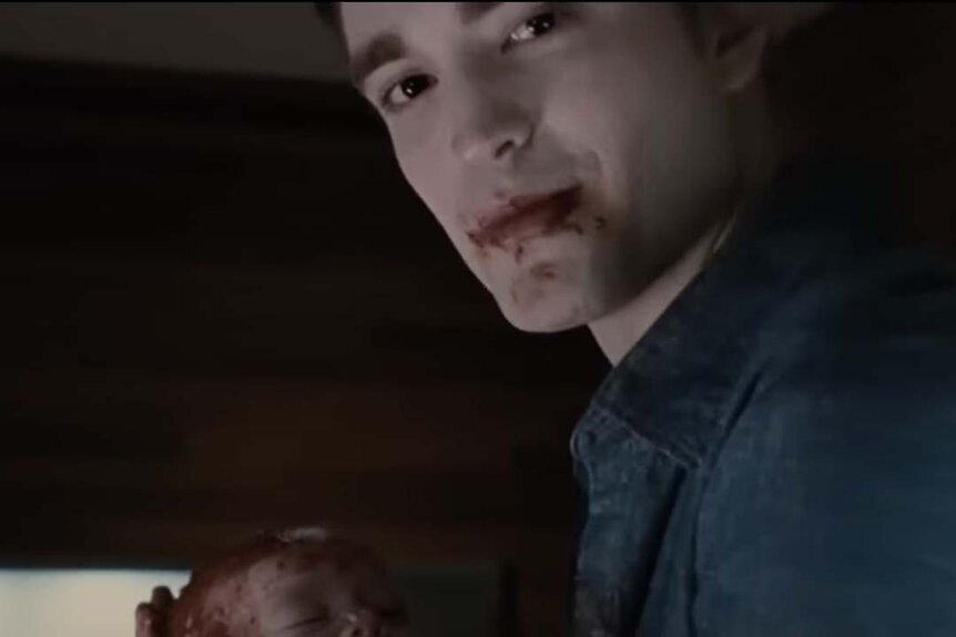 Edward Cullen (Robert Pattinson) has blood on his mouth as he holds a bloody baby.