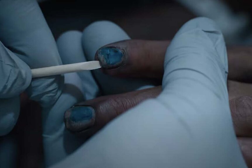 Gloved hands swabbing black nails in The Exorcist: Believer (2023)