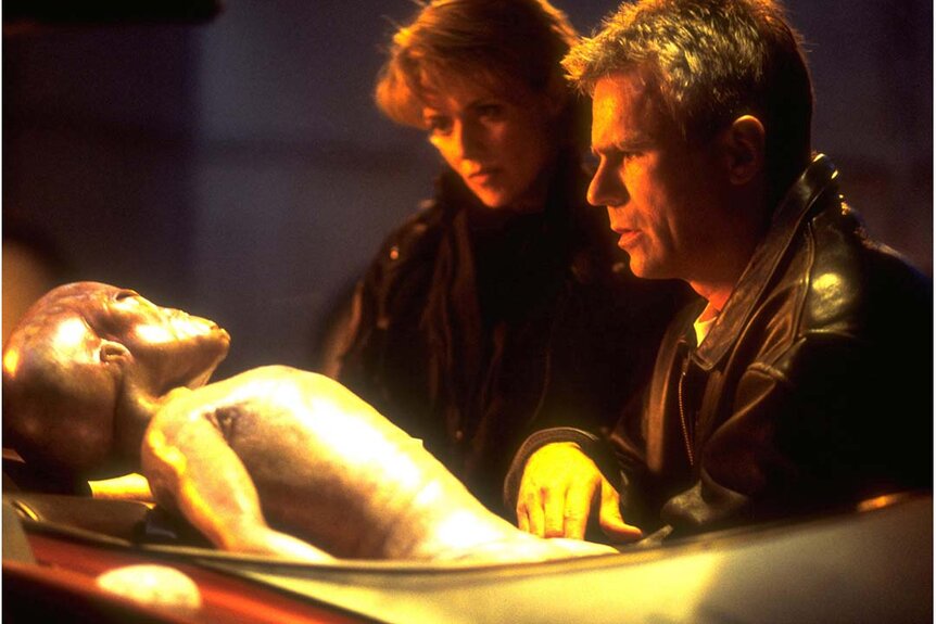 Amanda Tapping and Richard Dean Anderson looking at an alien body in Stargate SG-1