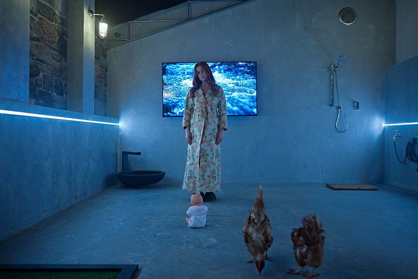 Mary (Isla Fisher) stands in front of a baby doll and chickens in Wolf Like Me Season 2