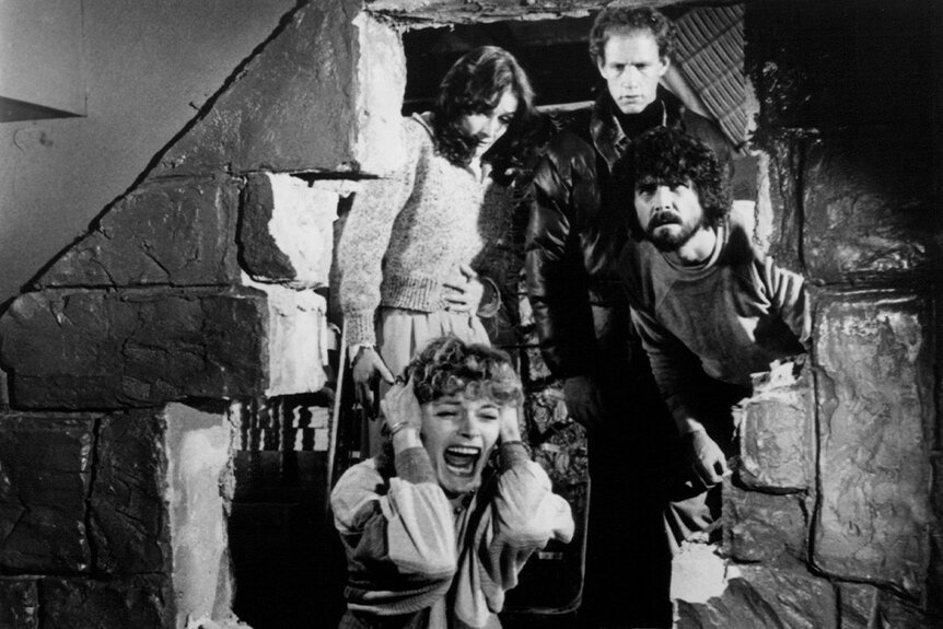 Helen Shaver screaming with fear while (L-R) Margot Kidder, Michael Sacks and James Brolin looking through the broken wall in The Amityville Horror (1979)