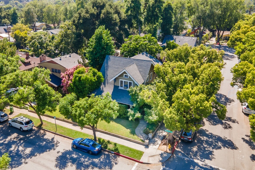 An exterior bird's eye view of the houses surrounded by trees in a suburban neighborhood.