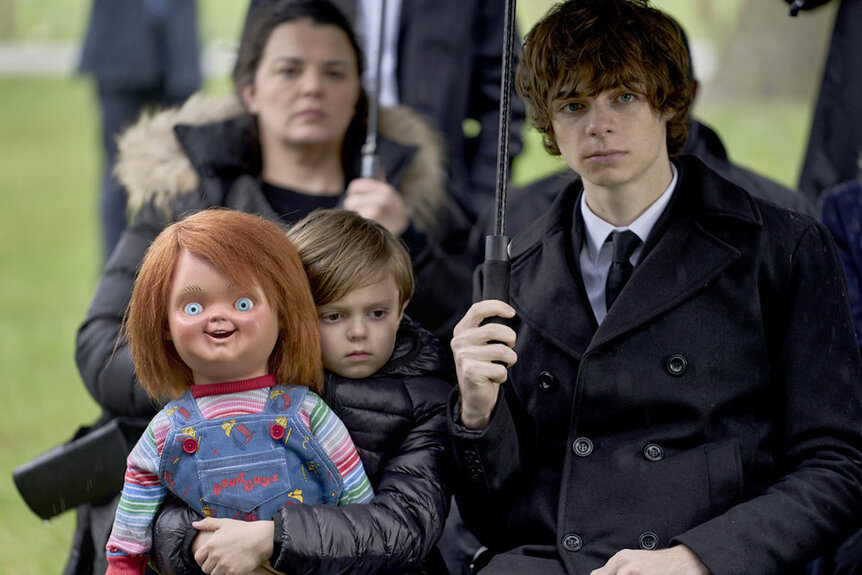 Henry Collins (Callum Vinson) holds Chucky as brother Grant Collins (Jackson Kelly) holds an umbrella in Chucky 301.