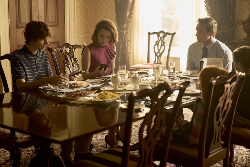 James Collins (Devon Sawa) sits at a dining table with Grant Collins (Jackson Kelly) and Charlotte Collins (Lara Jean Chorostecki).