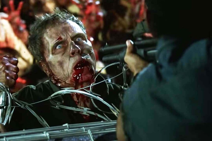 A wide-eyed zombie faces the barrel of a shotgun in Dawn of the Dead (2004).