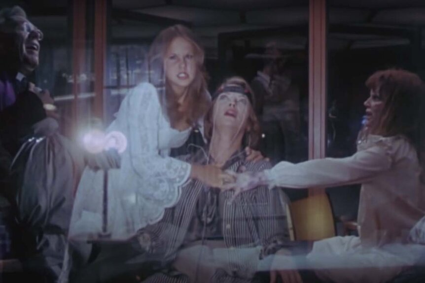 Linda Tuskin (Joey Lauren Adams) is pulled by Regan MacNeil (Linda Blair) and a demon Regan as Father Philip Lamont (Richard Burton) prays in Exorcist II The Heretic (1977)