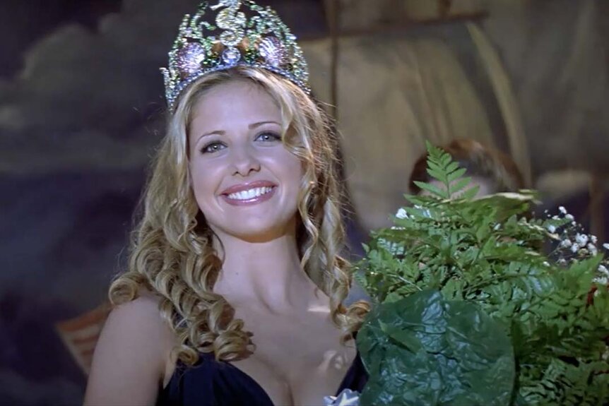 Helen Shivers (Sarah Michelle Gellar) smiles with a crown on her head and bouquet in her hands in I Know What You Did Last Summer (1997).