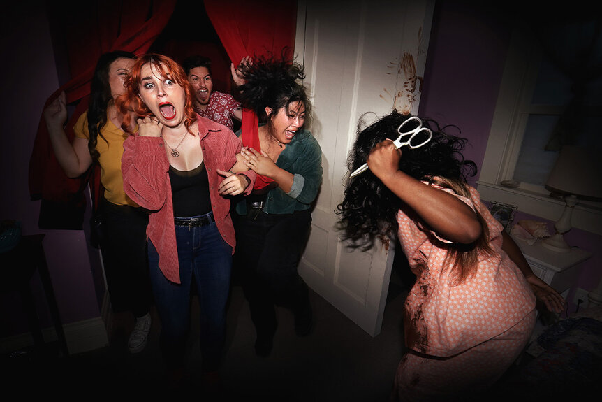 A group of women scream as a monster with scissors surprises them in  The Exorcist Haunted House at Halloween Horror Nights 2023.