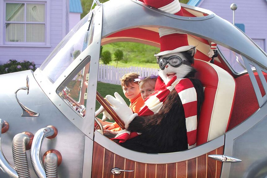 The Cat in the Hat (Mike Myers) wears goggles in a wacky silver vehicle with Conrad (Spencer Breslin) and Sally Walden (Dakota Fanning) as passengers in The Cat in the Hat (2003).