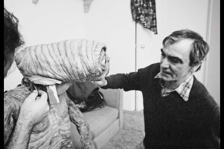 Carlo Rambaldi touches one of his E.T. puppets.