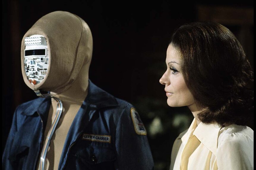 Dr. Leslie Dwyer (Corinne Camacho) (R) looks at a humanoid A.I. robot with hardware for a face in Kolchak: The Night Stalker Season 1.