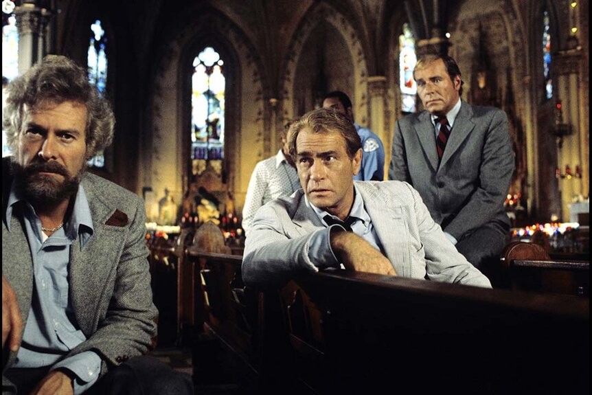 Crime reporter Carl Kolchak (Darren McGavin) (center) sits in a pew of a church with Ryder Bond (Fred Beir) Sgt. Mayer (Phil Carey).