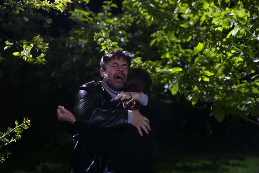 A frightened man hugs someone tightly in John Carpenter's Suburban Screams 106