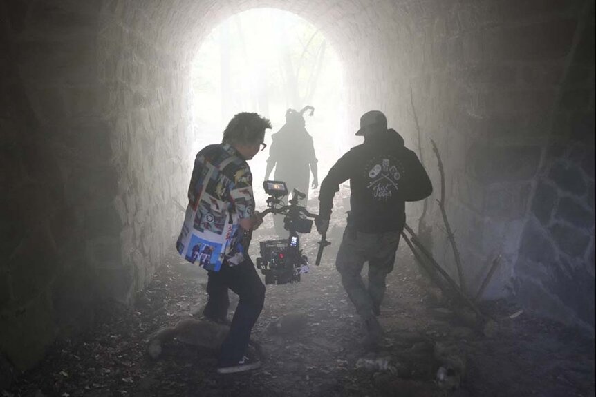 A film crew follows an actor wearing a "bunny ear" mask through a tunnel in John Carpenter's Suburban Screams 104.wres