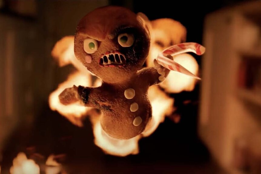 A flaming evil gingerbread man with a candy cane shiv flies through the air in Krampus (2015).
