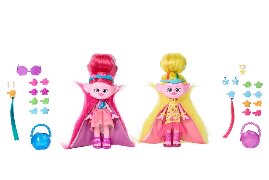 Two Trolls dolls, one with pink hair (L) one with yellow hair (R) with accessories scattered next to them.