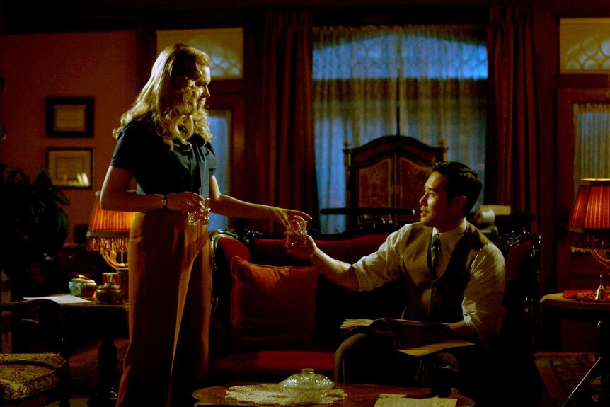 Hannah Carson standing next to Dr. Ben Song holding each other's hand in a dimly lit room.