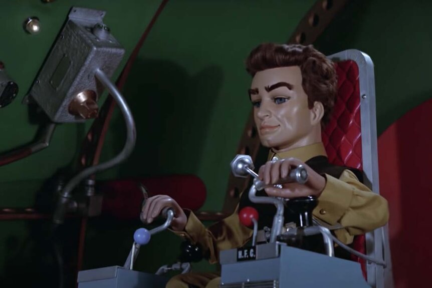 A puppet from Thunderbirds (1965) sits in a rocketship operation chair.
