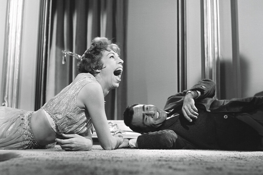 Carol Burnett and Rod Serling laugh on the floor together.