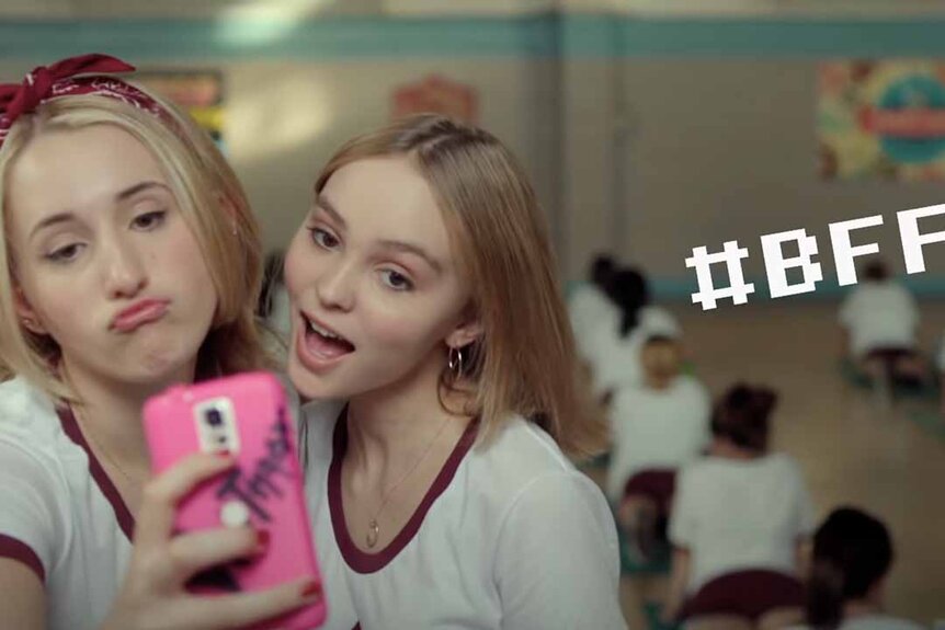 Collen McKenzie (Harley Quinn Smith) and Colleen Collette (Lily-Rose Depp) take a selfie on a pink Android while a #BFF graphic appears next to them in Yoga Hosers (2016).