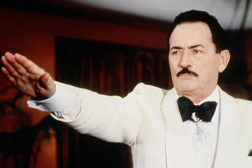 Dr. Josef Mengele (Gregory Peck) gives a Nazi salute in a white suit in The Boys from Brazil (1978).