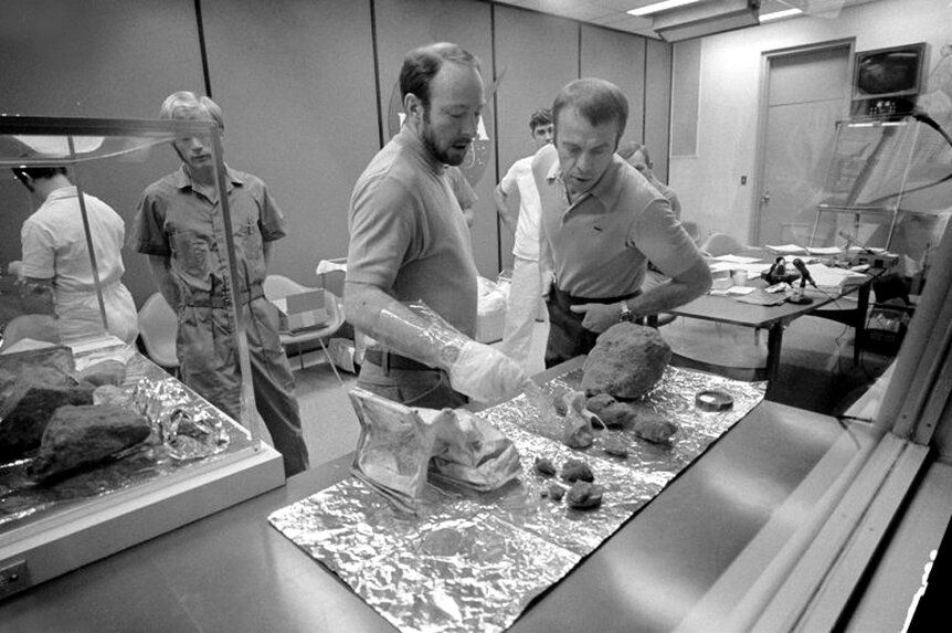 Astronauts Edgar Mitchell and Alan Shephard observing Moon rock samples.