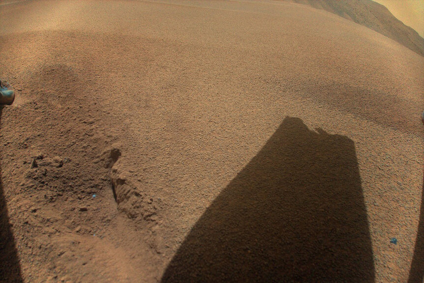 The shadow of a rotor blade of NASA’s Ingenuity Mars Helicopter