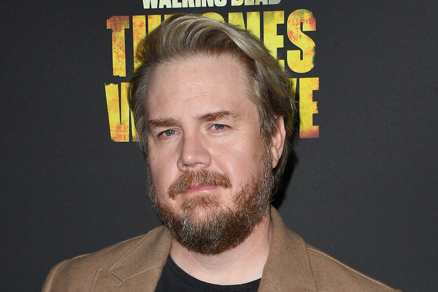 Josh McDermitt wears a brown jacket on the red carpet for The Walking Dead Live: The Finale Event