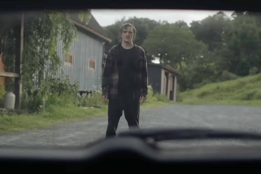 Emmett (Kyle Gallner) appears standing outside in a rearview mirror reflection in Mother, May I? (2023).