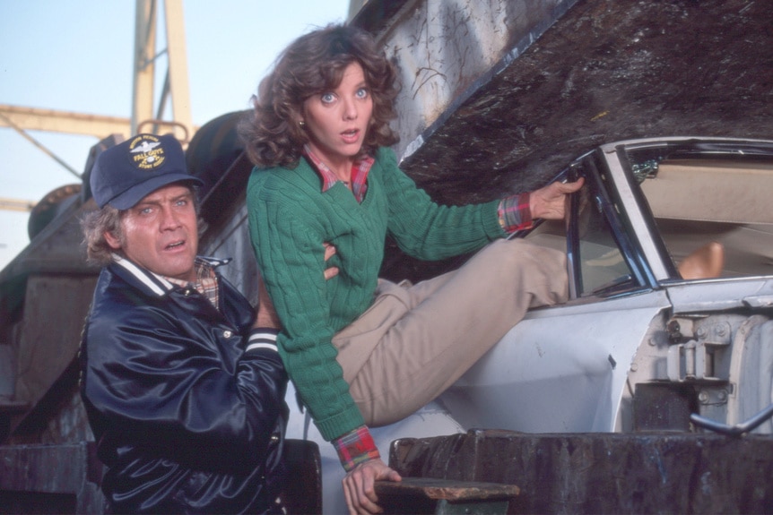 Lee Majors takes Judith Chapman out of a car on the fall guy