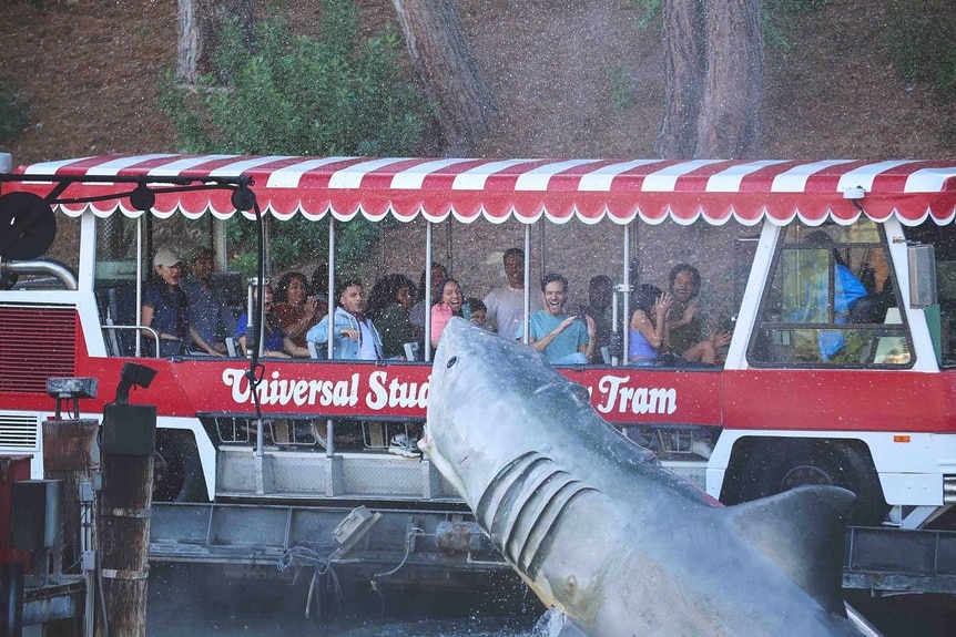 Guests ride the Universal Studios backlot tram at Jaws lake.