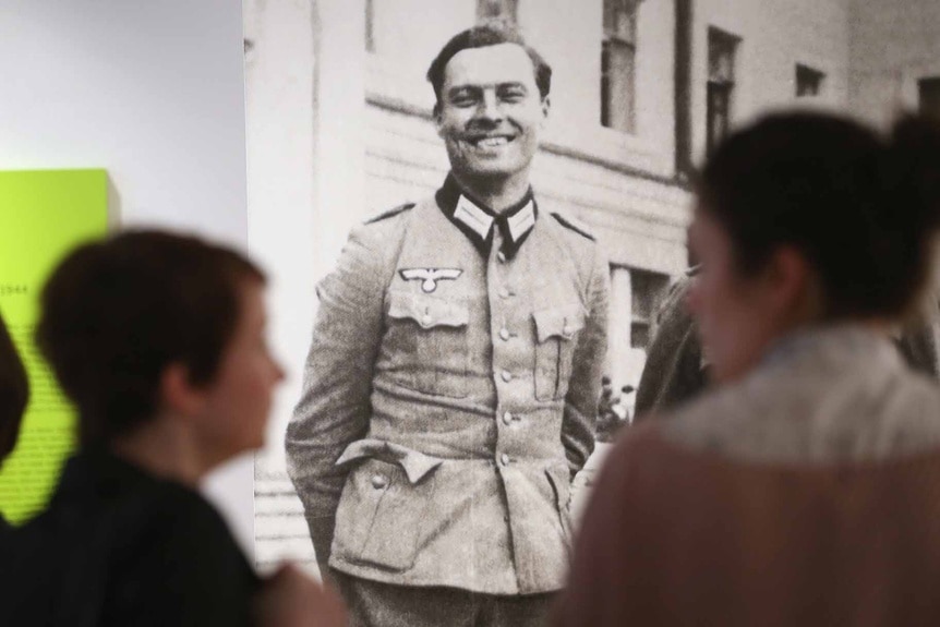 Visitors walk past a photograph of Claus von Stauffenberg.