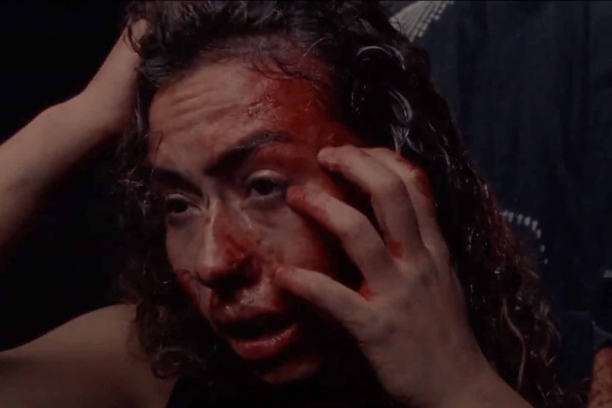 Dezzy (Dora Madison Burge) claws at her bloodied head in Bliss (2019).