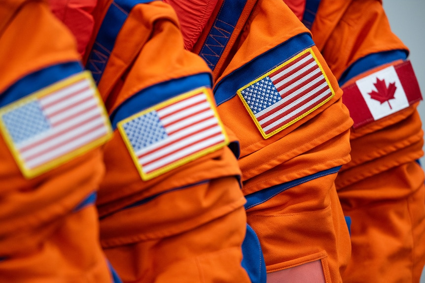 Artemis II suits with three American flag patches, plus one Canadian flag patch.