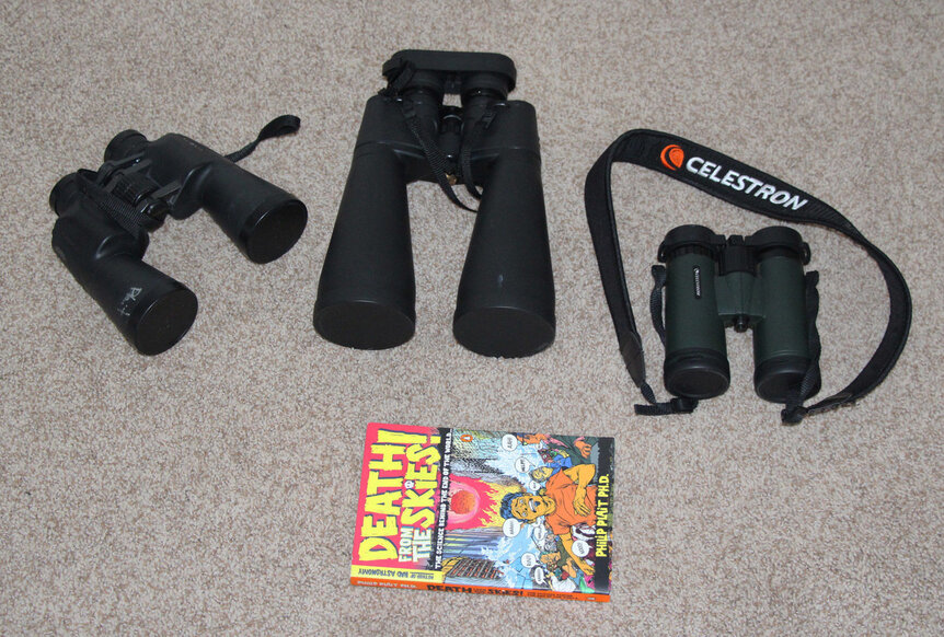 My binoculars described in the text; from left to right: 10x50, 15x70, 8x42; the book is one I completely at random picked up for size comparison. Credit: Phil Plait