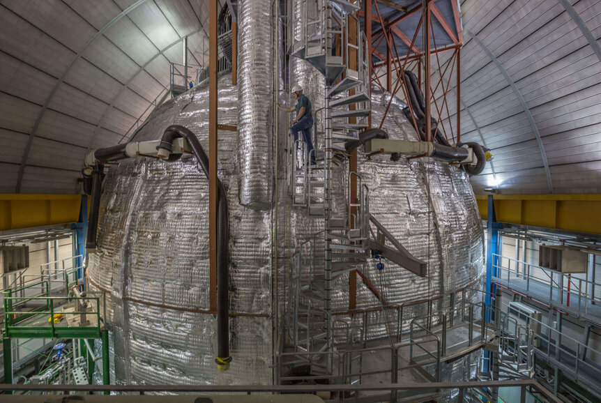 A photo of the Borexino detector, basically the outer water tank covered in insulation. Human included for scale. Credit: Agostini et al. 