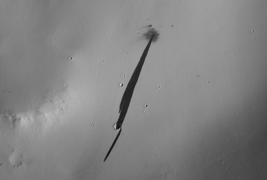 A tiny asteroid impacted Mars, releasing an avalanche of dust that left behind a dark streak on the surface. Credit: NASA/JPL/University of Arizona