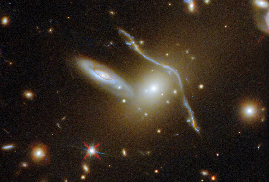 A galaxy in the cluster Abell S0295 gravitationally lenses a more distant galaxy, turning it from a spiral into a sinuous snake around it. Credit: SA/Hubble & NASA, F. Pacaud, D. Coe