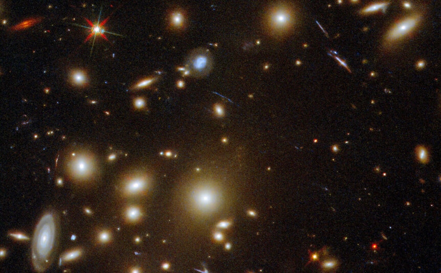 A foreground star (upper left) betrays its nature via diffraction spikes, an optical effect when a point source of light passes through a telescope.
